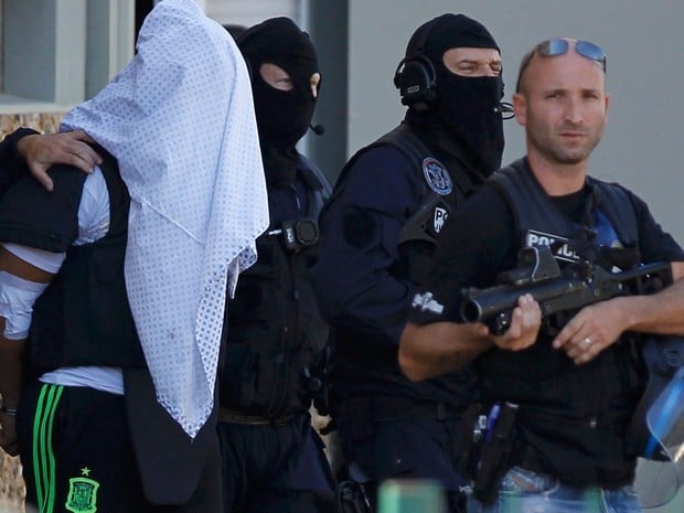 Com a cabeça coberta por uma camisa, Yassin Salhi é levado pela polícia francesa