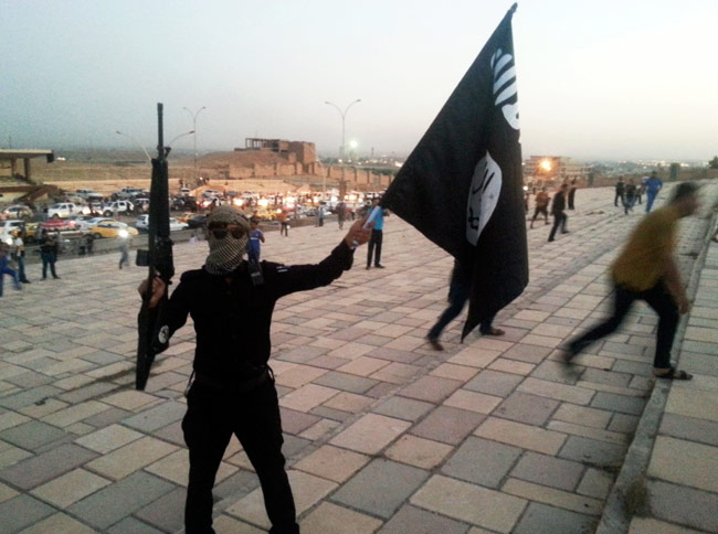 Militante do Estado Islâmico levanta bandeira do grupo terrorista no Iraque, país onde as casas de cristãos foram marcadas com o mesmo sinal correspondente à letra 'N' do alfabeto ocidental, como sigla para a palavra "nazareno" (Foto: Reuters)