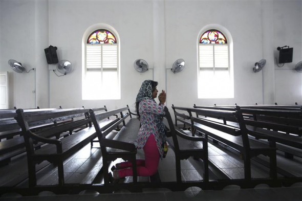 Imagem ilustrativa. Mulher orando em uma igreja na Malásia. (Foto: Reuters)