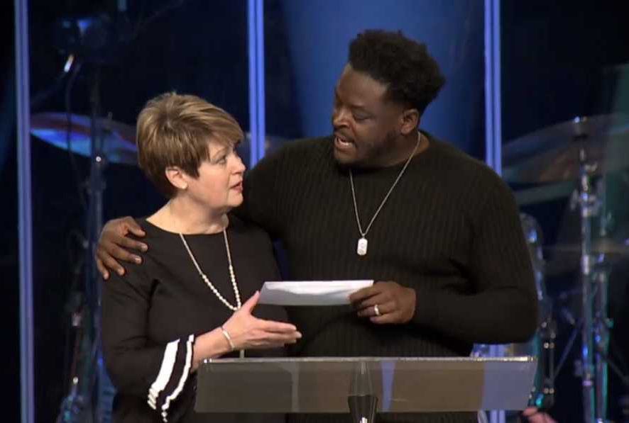 O pastor Derwin Gray entrega doação para Julie Walters, do Centro de Enriquecimento das Mulheres. (Foto: Reprodução/Facebook)