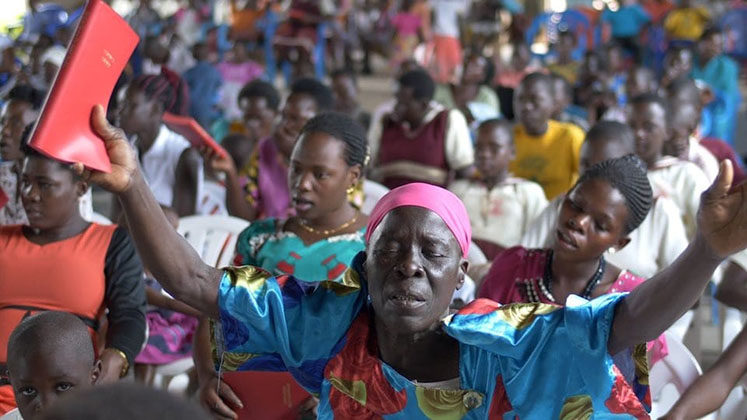 Mulher segura o Novo Testamento escrito em Lugwere pela primeira vez. (Foto: Reprodução/Wycliffe Bible Translators)