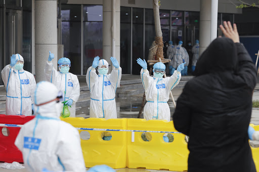 Paciente recuperado do coronavírus acena para equipe médica em frente a hospital temporário, em Wuhan. (Foto: Xinhua/Shen Bohan)