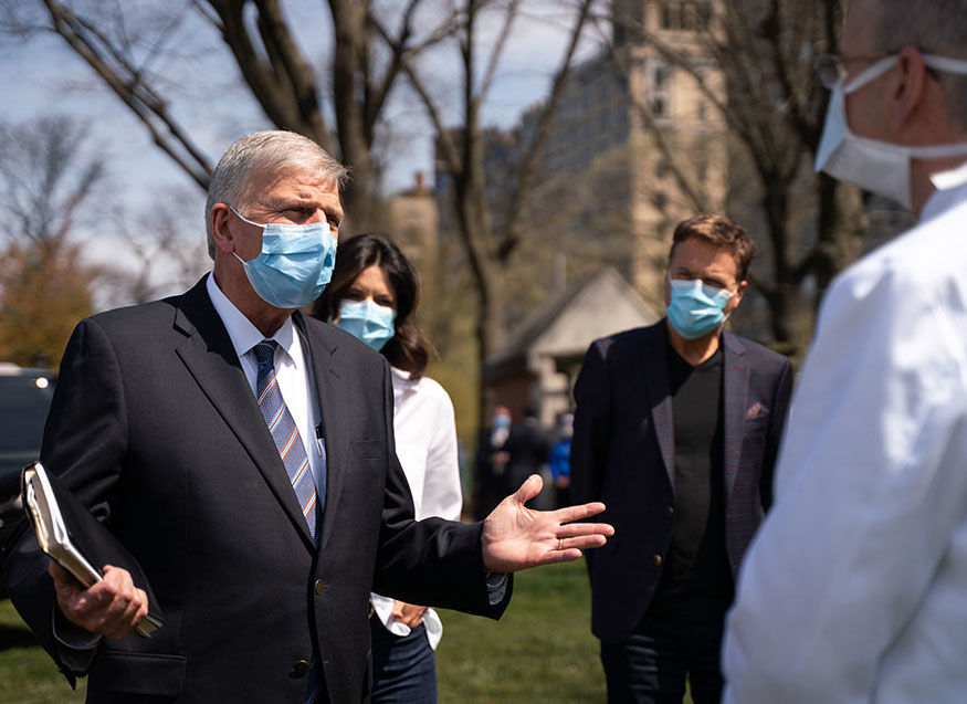 Usando máscaras, Pastor Franklin Graham (esquerda) é acompanhado do cantor Michael W. Smith (ao fundo) durante visita ao hospital de campanha montado pela Samaritan's Purse, organização missionária comandada pelo evangelista. (Foto: Samaritan's Purse)
