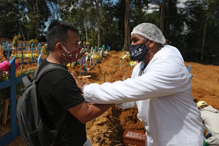 O pastor Izaías Nascimento conforta um jovem durante o funeral de seu pai. (Foto: Michael Dantas/AFP)