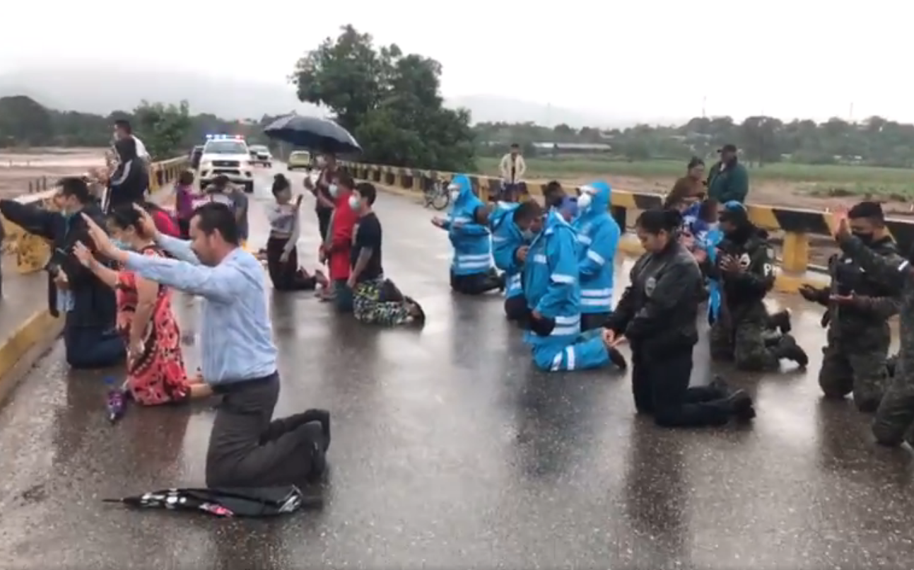 Policiais oram com cristãos em uma ponte sobre o rio Ulúa. (Foto: Policía Nacional de Honduras)