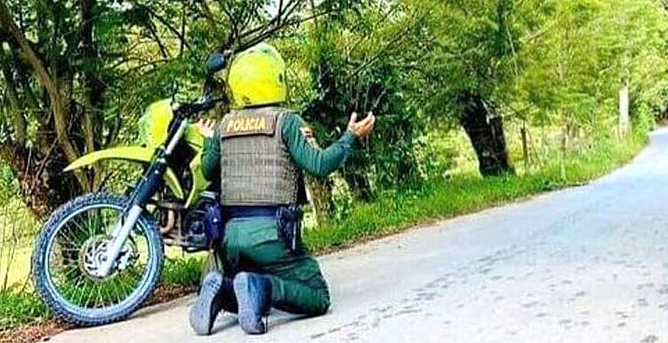 Policial se ajoelha para orar na Colômbia, em meio à onda de mortes no país