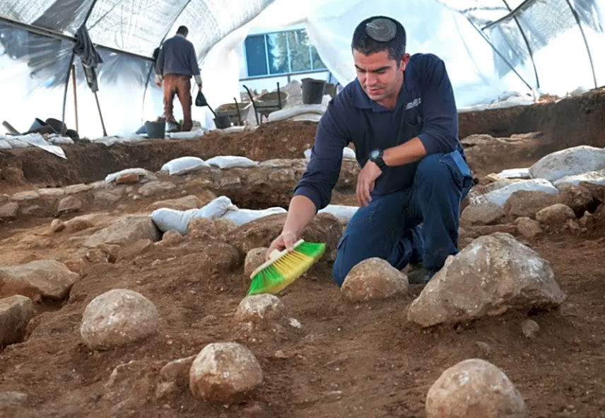 Kfir Arbiv, diretor de escavação da Autoridade de Antiguidades de Israel, limpa uma pedra balista no Complexo Russo. (Foto: Yoli Schwartz/Israel Antiquities Authority)